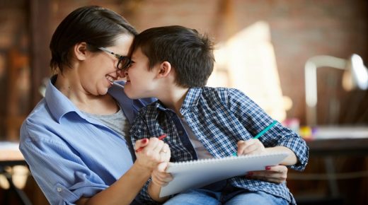 Side view portrait of adorable family scene, mother and son cuddling while painting pictures together