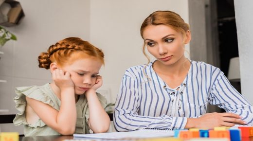 beautiful young mother looking sceptical on sad little daughter