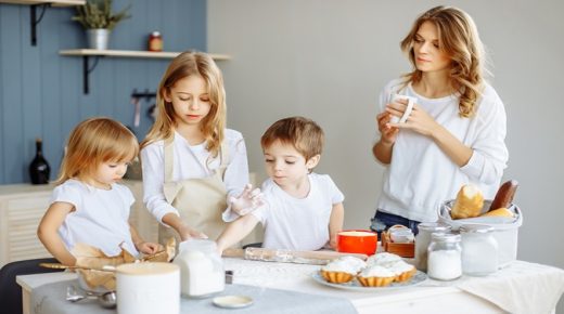 Happy family in the kitchen. Mother and her cute kids are cooking cookies