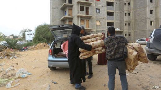 Displaced Libyans unload furniture, provided by as aid by a Libyan man, in an unfinished building in the Libyan capital Tripoli on December 18, 2019. - More than 140,000 Libyans like Mohammed have fled their homes since April, when the forces of eastern-based strongman Khalifa Haftar launched an assault on Tripoli, the seat of the UN-recognised government. In central Tripoli, the grey skeletons of a highrise construction site -- abandoned since 2008 due to a property dispute -- now host more than 170 families. (Photo by Mahmud TURKIA / AFP)