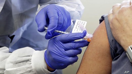 Neal Browning receives a shot in the first-stage safety study clinical trial of a potential vaccine for COVID-19, the disease caused by the new coronavirus, Monday, March 16, 2020, at the Kaiser Permanente Washington Health Research Institute in Seattle. Browning is the second patient to receive the shot in the study. (AP Photo/Ted S. Warren)