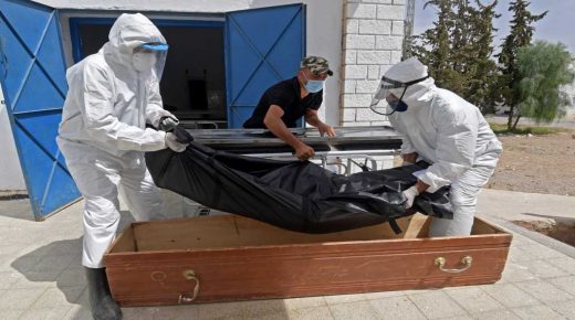 Tunisian municipality employees place the body of a COVID-19 victim into a casket at the Ibn al-Jazzar hospital in the east-central city of Kairouan on July 4, 2021. - Tunisia placed the capital Tunis and the northern town of Bizerte under a partial lockdown from until July 14 in a bid to rein in record daily coronavirus cases and deaths. (Photo by FETHI BELAID / AFP)