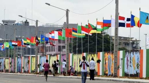 People walk past a wall bearing paintings near the National Institute of Youth and Sports on July 17, 2017 in Abidjan ahead of the Jeux de la Francophonie (French-speaking countries Games). - The 2017 Jeux de la Francophonie will be held in Abidjan from July 21 until July 30, 2017. (Photo by SIA KAMBOU / AFP)
