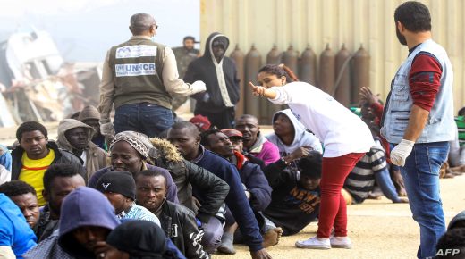 Workers from the office of the United Nations High Commissioner for Refugees (UNHCR) tend to African migrants rescued from a ship off the coast of Zawiyah, about 45 kilometres west of the Libyan capital Tripoli, as they sit at the dock at the capital's naval base on March 10, 2018. / AFP PHOTO / MAHMUD TURKIA