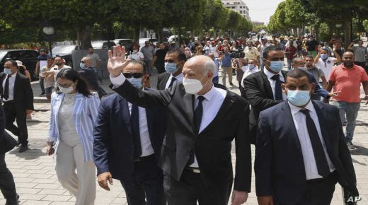 Tunisian President Kais Saied waves to bystanders as he stroll along the avenue Bourguiba in Tunis, Tunisia, Sunday, Aug. 1, 2021. President Kais Saied claimed on Sunday that some desperate youth are being paid to try to leave Tunisia illegally for Europe, saying the goal is to damage the country from within. (Slim Abid/Tunisian Presidency via AP)
