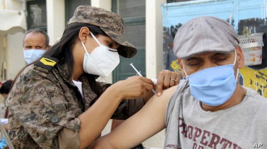 A soldier administrates the Vaxzevria COVID-19 vaccine to a man at the Assad Iben El Fourat school in Oued Ellil, outside Tunis, Sunday, Aug.8, 2021. Tunisia has launched its largest COVID-19 vaccination campaign as the country faces a surge of cases. Authorities aim to vaccinate over 1 million of people aged 40 and over in only one day, compared with 30,000 to 60,000 a day previously. (AP Photo/Hassene Dridi)