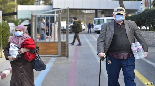Poeple waering wearing protective masks walk out of the El-Kettar hospital in the Algerian capital Algiers on February 26, 2020. - Algerian authorities announced yesterday the country's first case of the novel coronavirus, in an Italian citizen who arrived in the country on February 17. (Photo by RYAD KRAMDI / AFP)