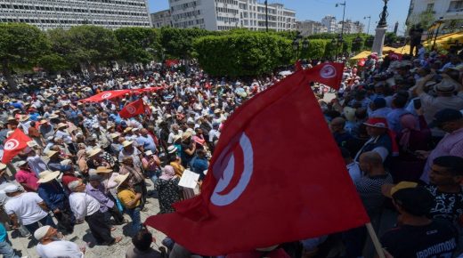 Tunisian protesters lift national flags during a demonstration in the capital Tunis on June 19, 2022, against President Kais Saied and the upcoming July 25 constitutional referendum. (Photo by FETHI BELAID / AFP)