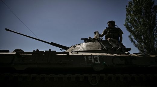 TOPSHOT - A member of the Ukrainian troops stands on an armoured vehicle moving towards the front line in the city of Lysychansk in the eastern Ukraine region of Donbas on June 9, 2022, as Russian forces have for weeks been concentrating their firepower on Severodonetsk and its sister city of Lysychansk across the river. - A defiant Lugansk governor declares that Ukrainian forces could reclaim Severodonetsk "in two to three days" if they receive long-range artillery promised by the US and Britain. (Photo by ARIS MESSINIS / AFP) (Photo by ARIS MESSINIS/AFP via Getty Images)