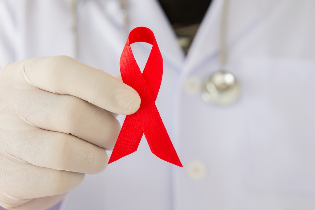 doctors hands holding red aids ribbon. world aids day concepts.